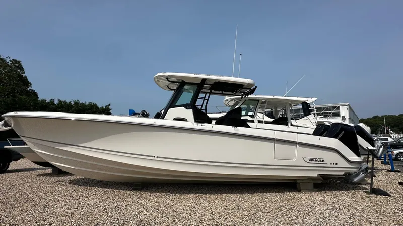 The Image of 2025 Boston Whaler 330 Outrage boat displayed on gravel lot. - 0