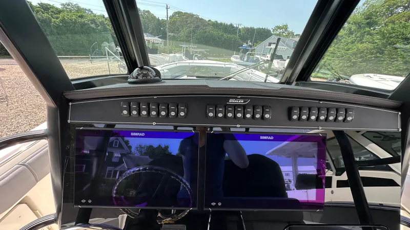 Slide: The Image of 2025 Boston Whaler 330 Outrage dashboard with dual Simrad displays and control panel. - 14