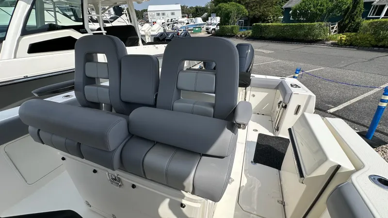 Slide: The Image of 2025 Boston Whaler 330 Outrage boat interior with gray seating in a marina setting. - 16