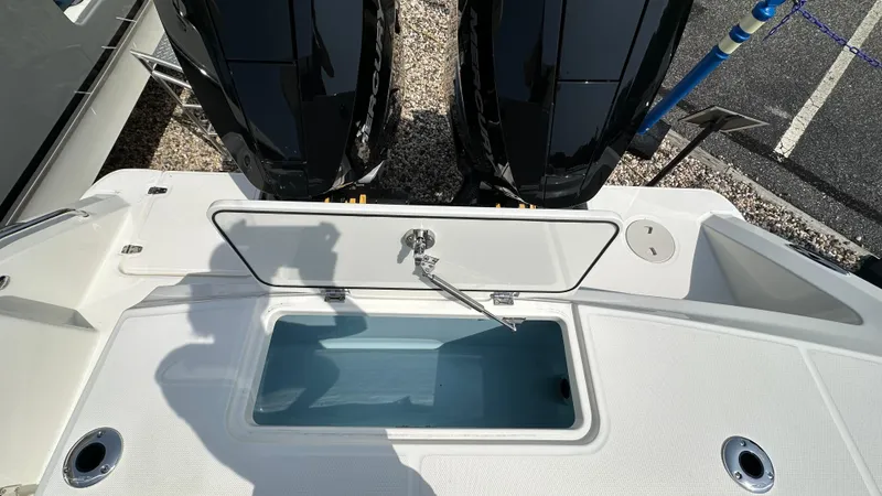 Slide: The Image of 2025 Boston Whaler 330 Outrage boat with open storage compartment and dual outboard engines. - 2
