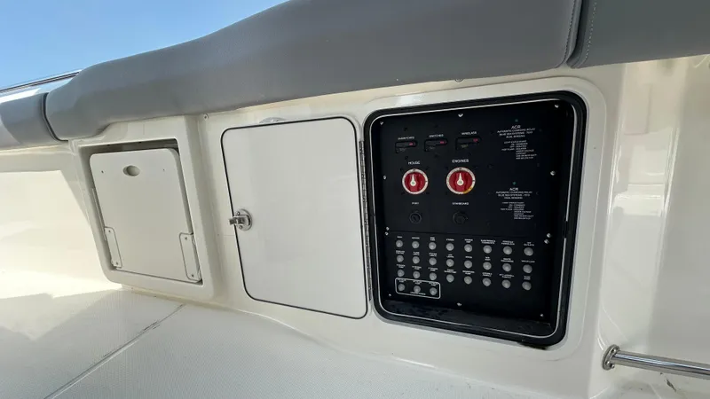 Slide: The Image of Control panel on 2025 Boston Whaler 330 Outrage boat, featuring switches and storage compartments. - 24