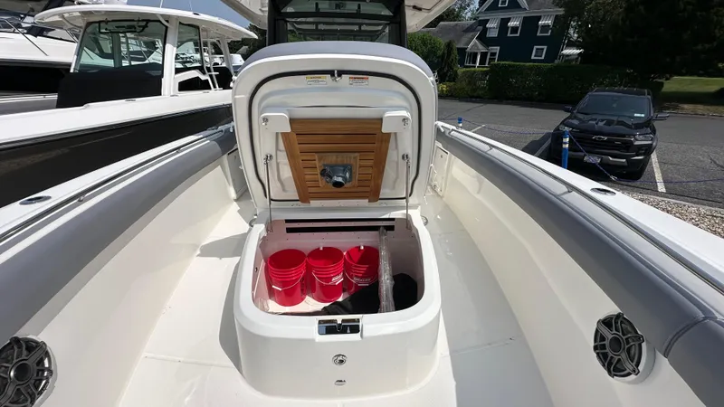 Slide: The Image of 2025 Boston Whaler 330 Outrage boat with open storage compartment and red buckets. - 30
