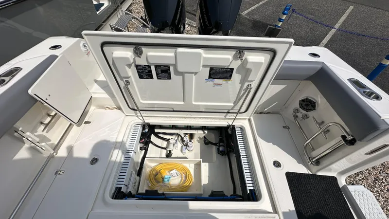 Slide: The Image of 2025 Boston Whaler 330 Outrage boat storage compartment with open hatch, revealing interior equipment. - 7