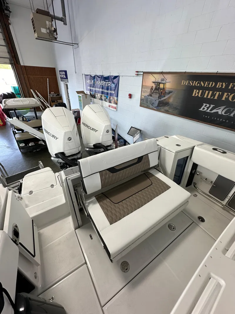 Slide: The Image of 2023 Blackfin 272 CC boat interior with twin Mercury engines in showroom. - 12