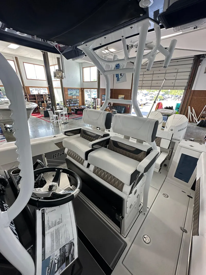 Slide: The Image of 2023 Blackfin 272 CC boat interior with dual seating and steering console in showroom. - 5