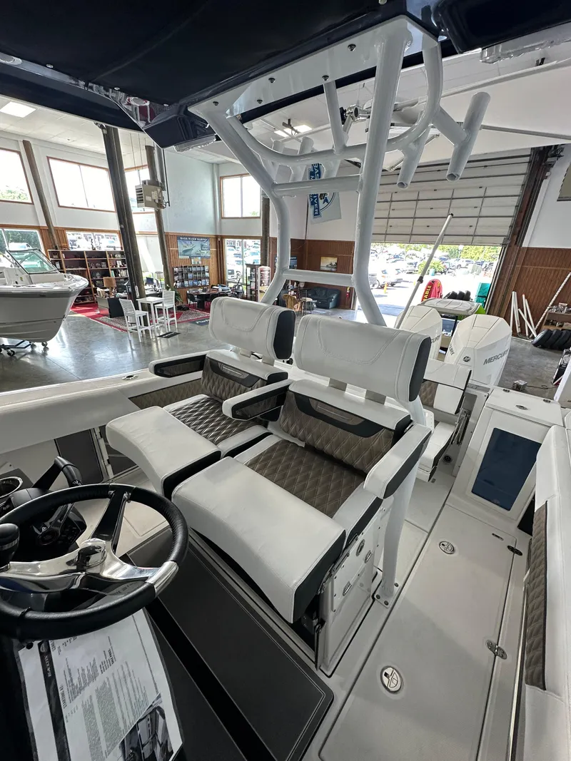 Slide: The Image of 2023 Blackfin 272 CC boat interior with dual seating and steering wheel in showroom. - 6