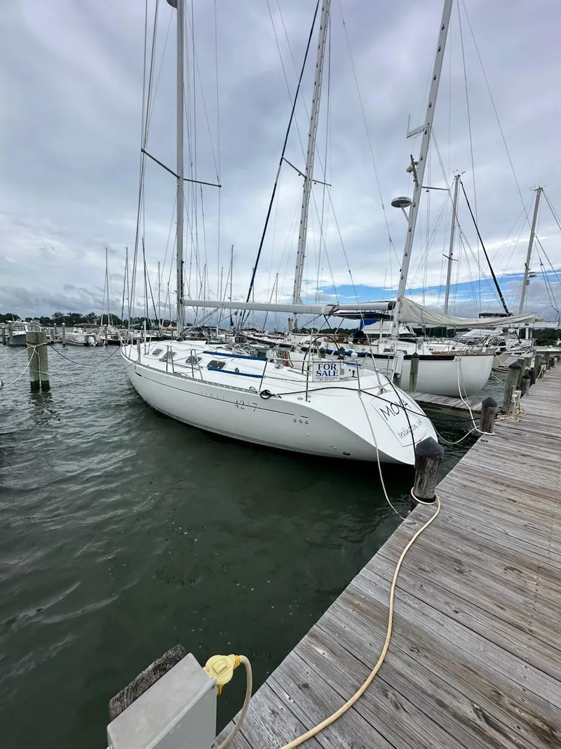The Image of 1997 Beneteau 42S7 sailboat docked at marina under cloudy sky. - 0
