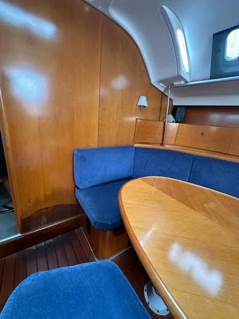 Slide: The Image of Interior of 1997 Beneteau 42S7 sailboat with blue seating and wooden table. - 10