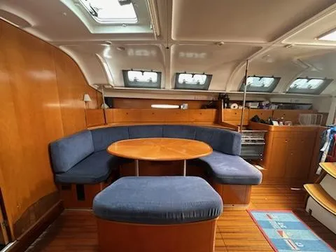 Slide: The Image of Interior of 1997 Beneteau 42S7 yacht with blue seating and wooden table. - 14