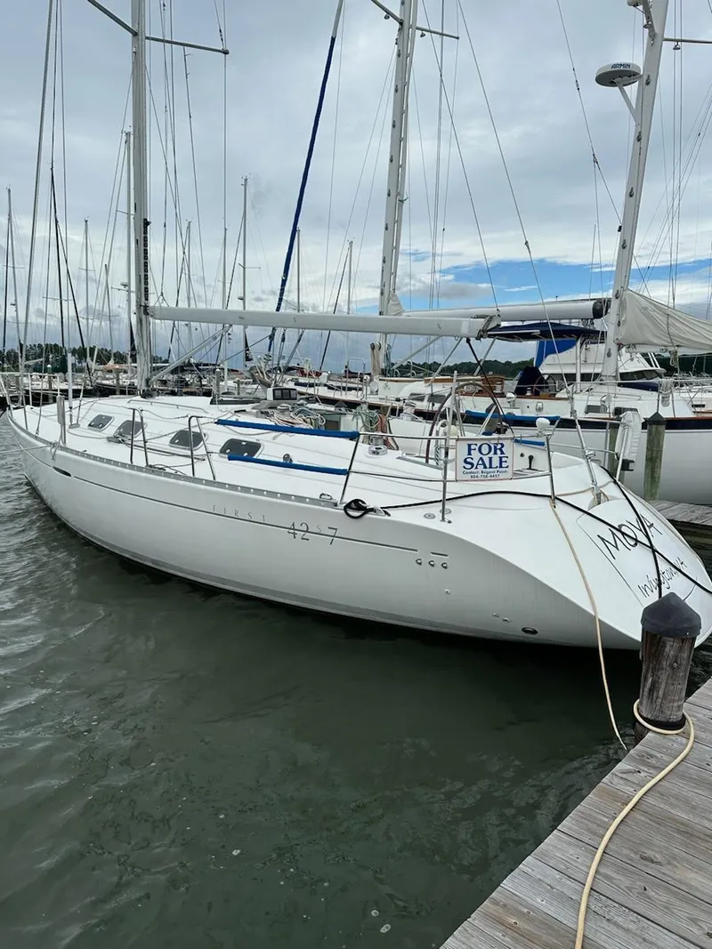 Slide: The Image of 1997 Beneteau 42S7 sailboat docked, for sale sign visible, overcast sky. - 26