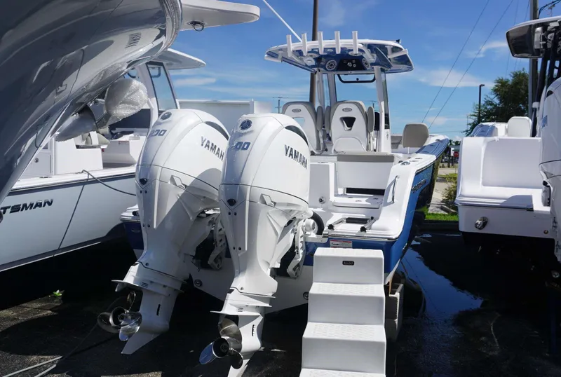 Slide: The Image of 2025 Sportsman 261 Heritage boat with twin Yamaha engines, docked under clear blue sky. - 2
