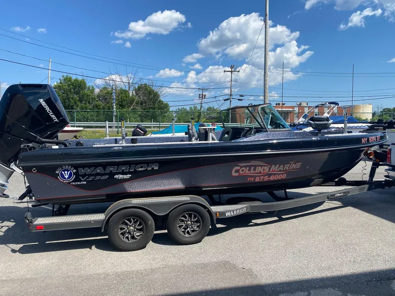 The Image of 2023 Warrior 238 DC boat on trailer under clear blue sky. - 2