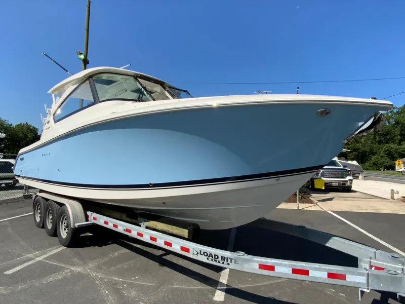 Slide: The Image of 2025 Pursuit DC 306 Dual Console boat on Load Rite trailer in parking lot. - 3