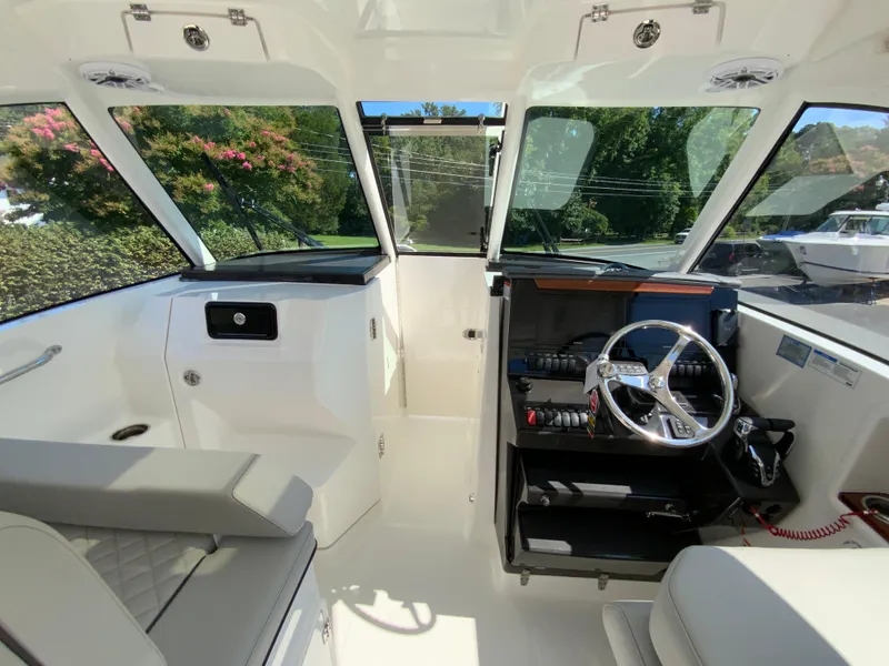 Slide: The Image of 2025 Pursuit DC 306 Dual Console boat interior with helm, seating, and panoramic windows. - 37