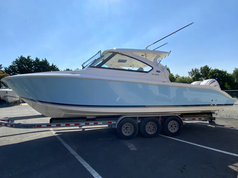 Slide: The Image of 2025 Pursuit DC 306 Dual Console boat on a trailer in a parking lot. - 6