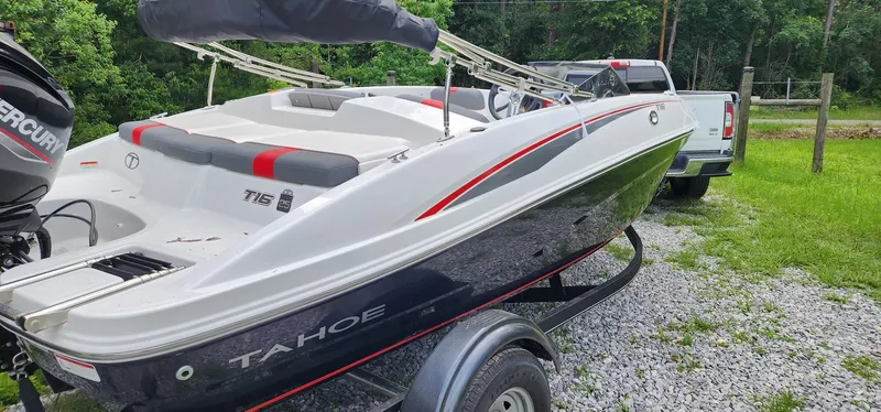 Slide: The Image of 2023 Tahoe T16 boat on trailer, attached to a white truck, parked on gravel. - 2