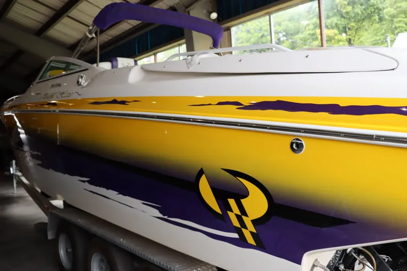 Slide: The Image of 2004 Powerquest 340 Vyper boat with vibrant yellow and purple graphics in a garage. - 22