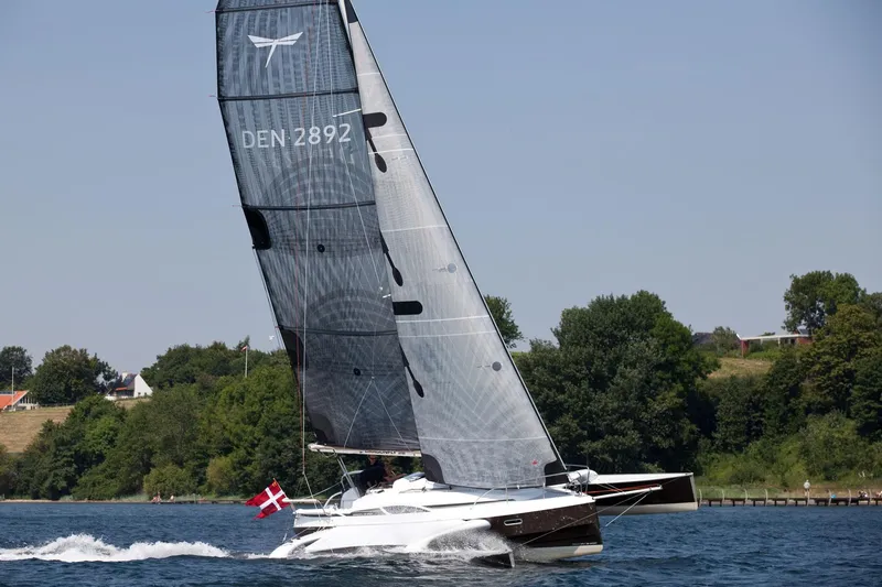 Slide: The Image of Sailing yacht Dragonfly 28, 2026 model, gliding on water with Danish flag. - 1