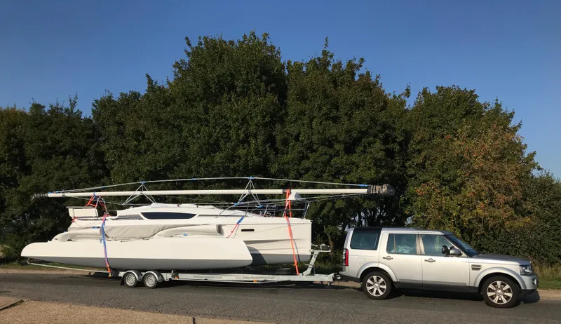 Slide: The Image of SUV towing a Dragonfly 28 trimaran on a trailer, parked on a road. - 15