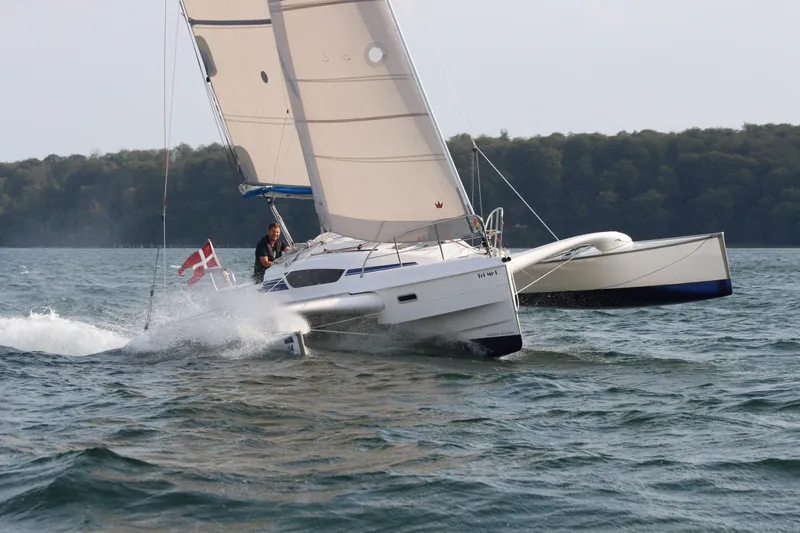 Slide: The Image of Sailing Dragonfly 28 trimaran on water, 2026 model, with Danish flag. - 2