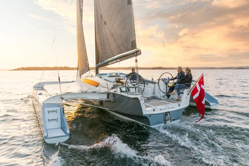 Slide: The Image of Sailing on a Dragonfly 40 trimaran at sunset, 2026 model, with Danish flag. - 2