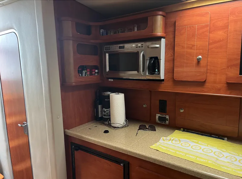 Slide: The Image of 2006 Rinker 390 Express Cruiser kitchen with microwave, countertop, and wooden cabinets. - 14