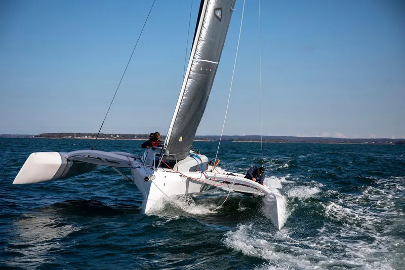 Slide: The Image of Sailing Corsair 880 trimaran on open water, 2025 model, under clear blue sky. - 1