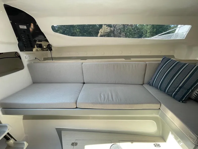 Slide: The Image of Interior of 2025 Corsair 880 sailboat with cushioned seating and striped pillow. - 12