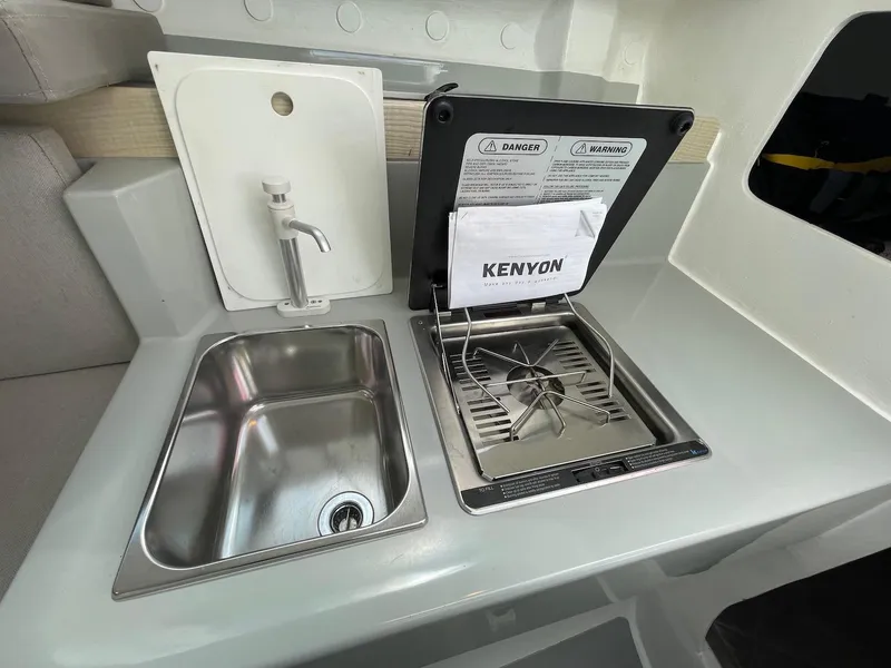 Slide: The Image of Compact kitchen area in a 2025 Corsair 880, featuring a sink and Kenyon stove. - 19