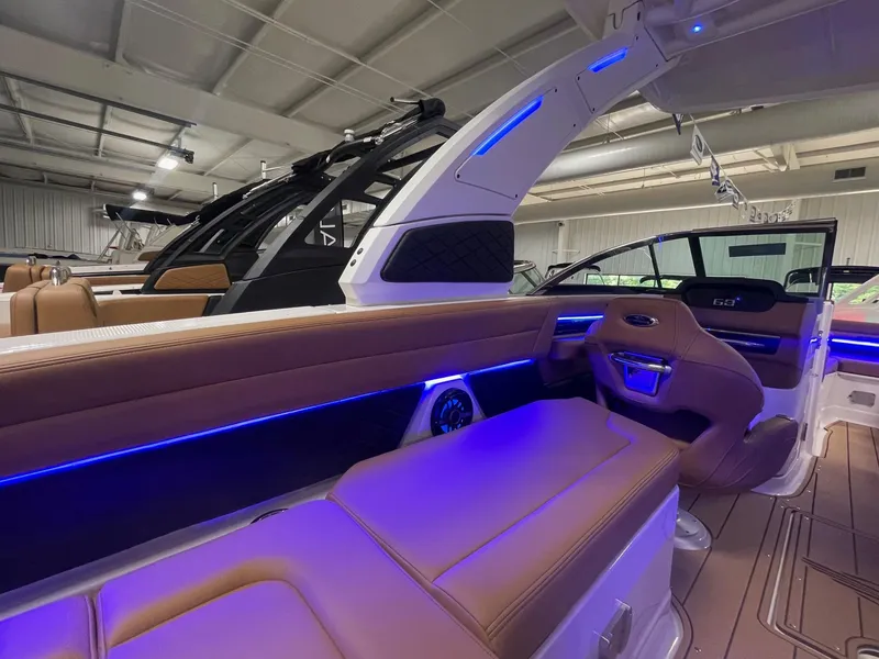 Slide: The Image of 2025 Chaparral 267 SSX boat interior with blue LED lighting and tan seating. - 10