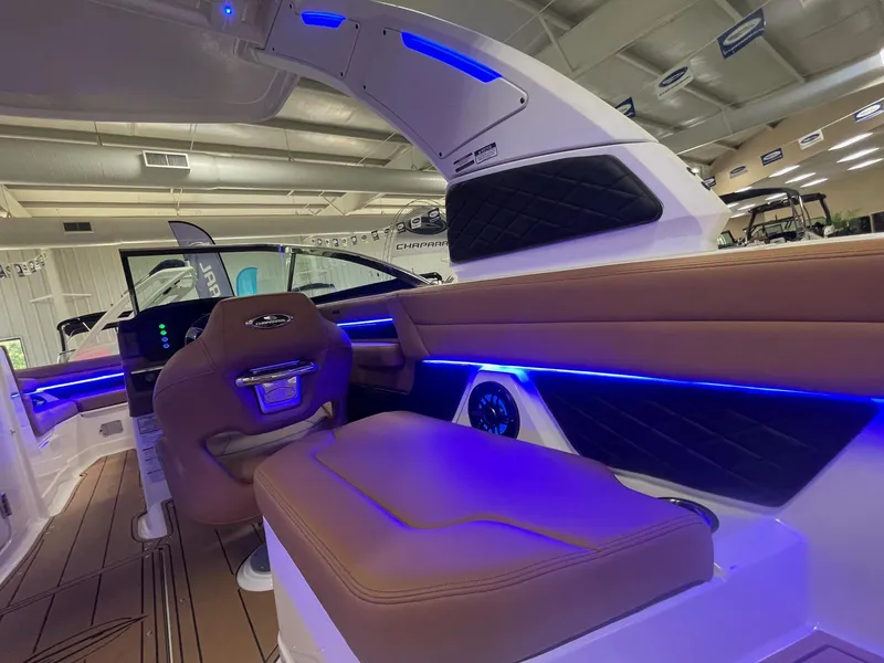 Slide: The Image of 2025 Chaparral 267 SSX boat interior with blue LED lighting and brown leather seating. - 11
