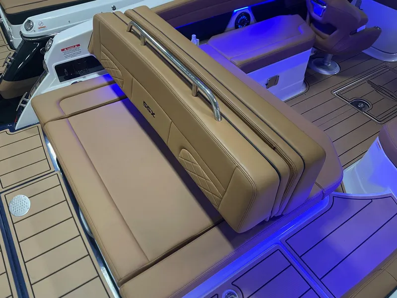 Slide: The Image of 2025 Chaparral 267 SSX boat interior with tan leather seating and blue LED lighting. - 15