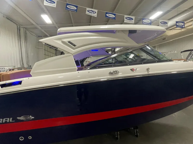 Slide: The Image of 2025 Chaparral 267 SSX boat in showroom, side view with blue and red hull. - 4