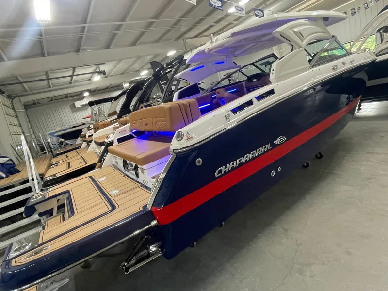 Slide: The Image of 2025 Chaparral 267 SSX boat in showroom, rear view with blue and red accents. - 7
