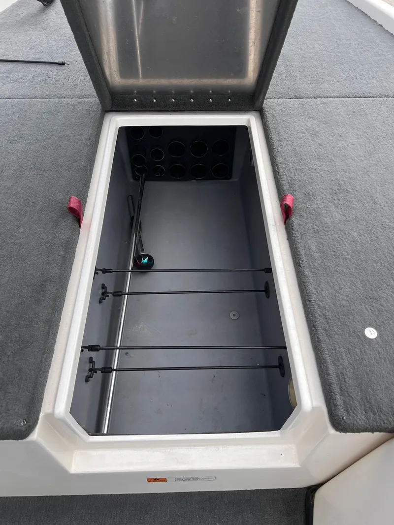 Slide: The Image of Open storage compartment in 2007 Stratos 176XT boat, featuring rod holders and carpeted interior. - 3