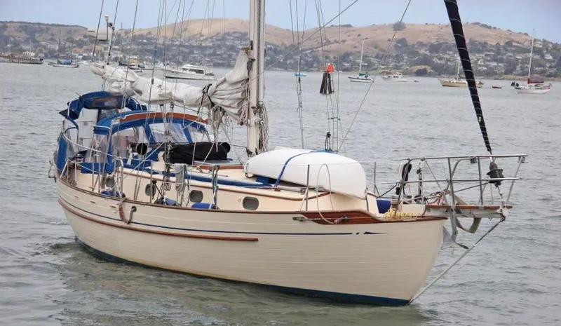 Slide: The Image of 1984 Tayana Sloop Rigged Cutter sailboat anchored in a scenic harbor. - 1