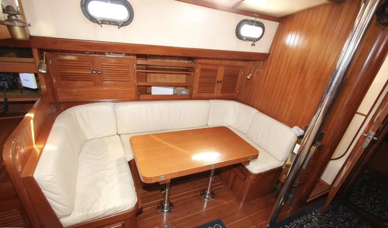 Slide: The Image of 1984 Tayana Sloop Rigged Cutter interior with wooden paneling and cozy seating area. - 10