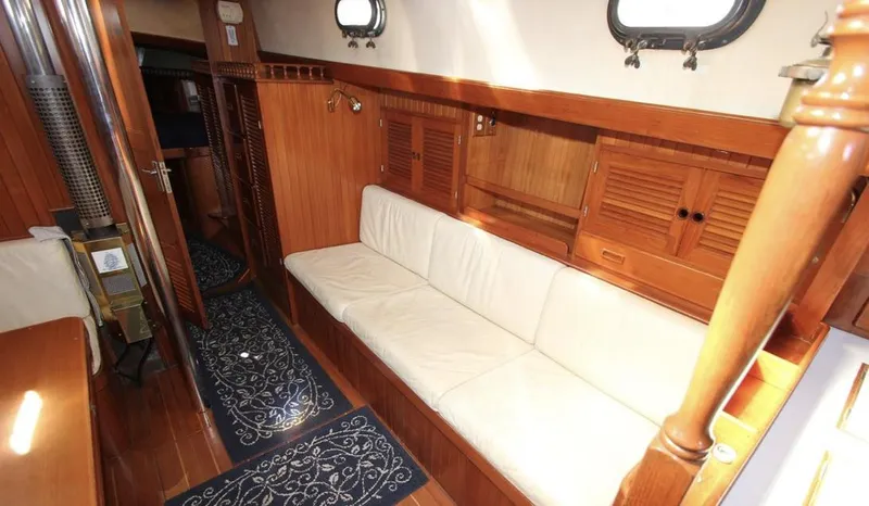 Slide: The Image of 1984 Tayana Sloop Rigged Cutter interior with wooden finish and white seating. - 11