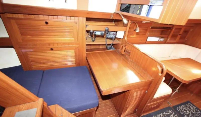 Slide: The Image of 1984 Tayana Sloop Rigged Cutter interior with wooden finish and seating area. - 16