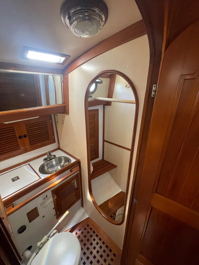 Slide: The Image of 1984 Tayana Sloop Rigged Cutter bathroom with wooden accents, sink, and mirror. - 18