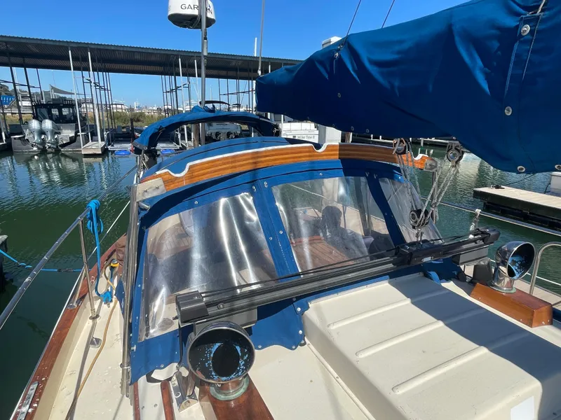 Slide: The Image of 1984 Tayana Sloop Rigged Cutter sailboat docked at marina, featuring blue canvas and clear panels. - 2