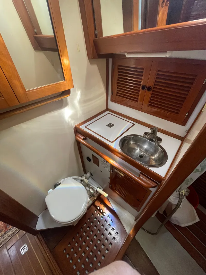 Slide: The Image of 1984 Tayana Sloop Rigged Cutter bathroom with wooden cabinetry, sink, and toilet. - 20