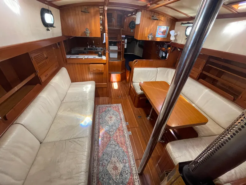 Slide: The Image of 1984 Tayana Sloop Rigged Cutter interior with wood finish, cozy seating, and dining area. - 22
