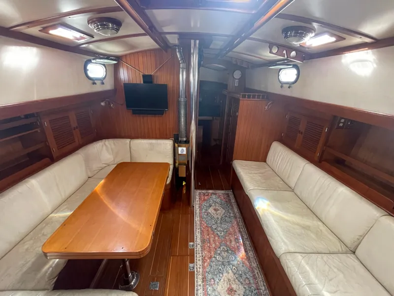 Slide: The Image of 1984 Tayana Sloop Rigged Cutter interior with wood finish, seating, and dining table. - 23