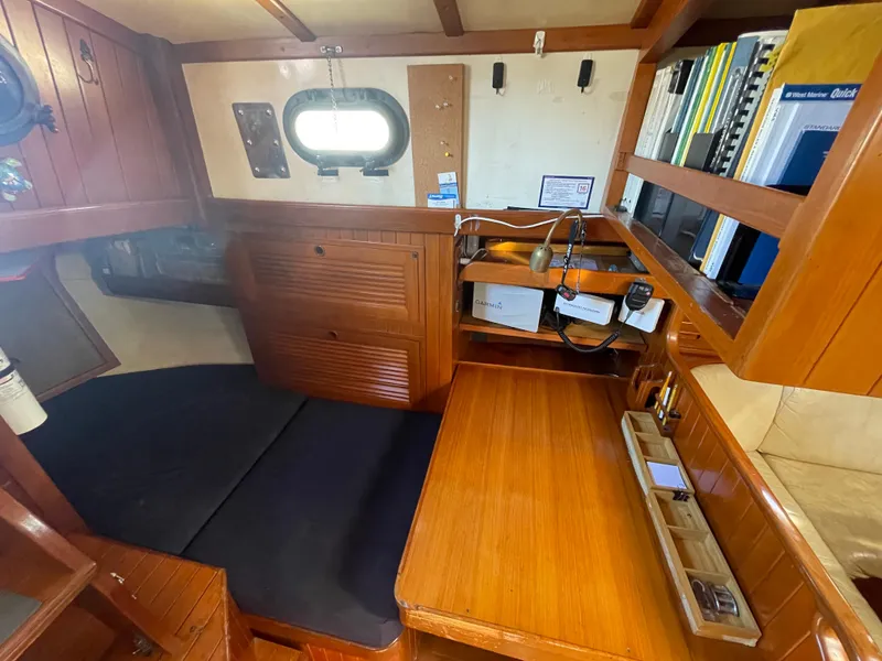 Slide: The Image of 1984 Tayana Sloop Rigged Cutter cabin interior with wooden desk, shelves, and porthole window. - 24