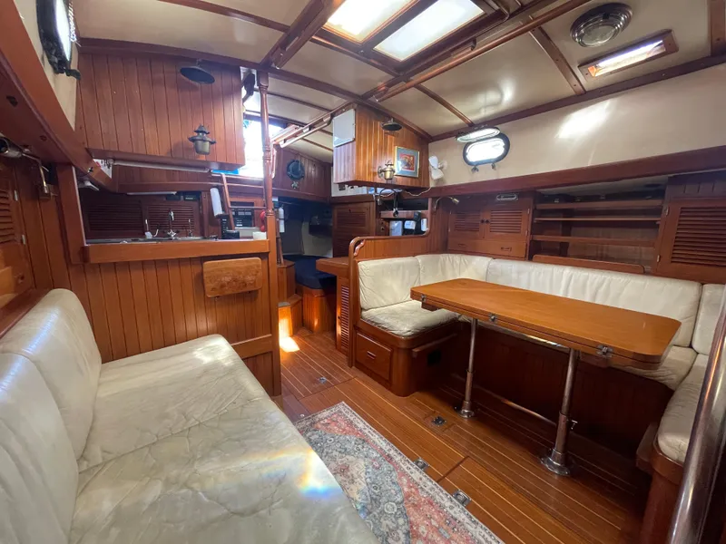 Slide: The Image of 1984 Tayana Sloop Rigged Cutter interior with wood paneling and cozy seating area. - 28
