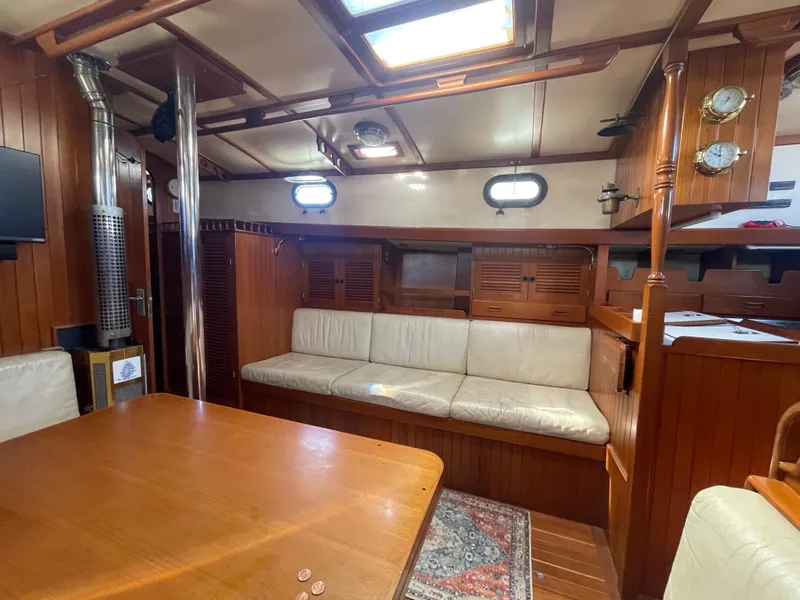 Slide: The Image of 1984 Tayana Sloop Rigged Cutter interior with wooden finish, cozy seating, and nautical decor. - 29