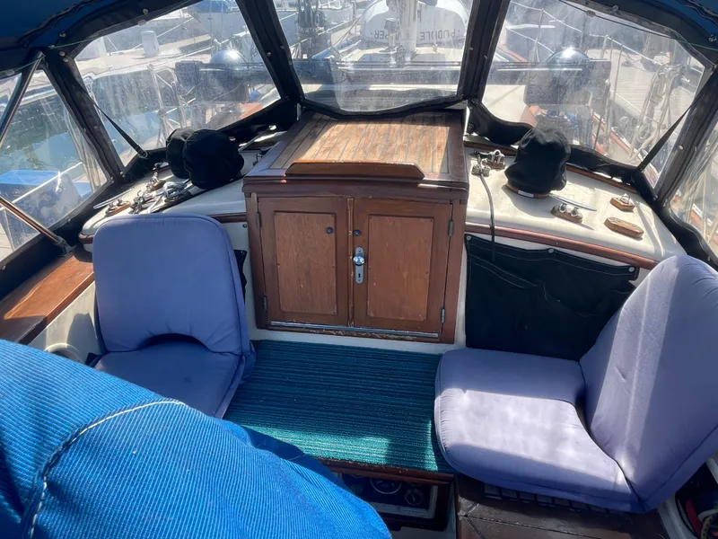 Slide: The Image of 1984 Tayana Sloop Rigged Cutter cockpit with blue seating and wooden cabinetry. - 4