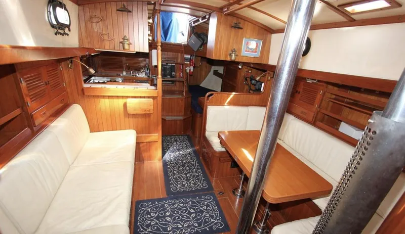 Slide: The Image of 1984 Tayana Sloop Rigged Cutter interior with wood finish, seating, and dining area. - 8