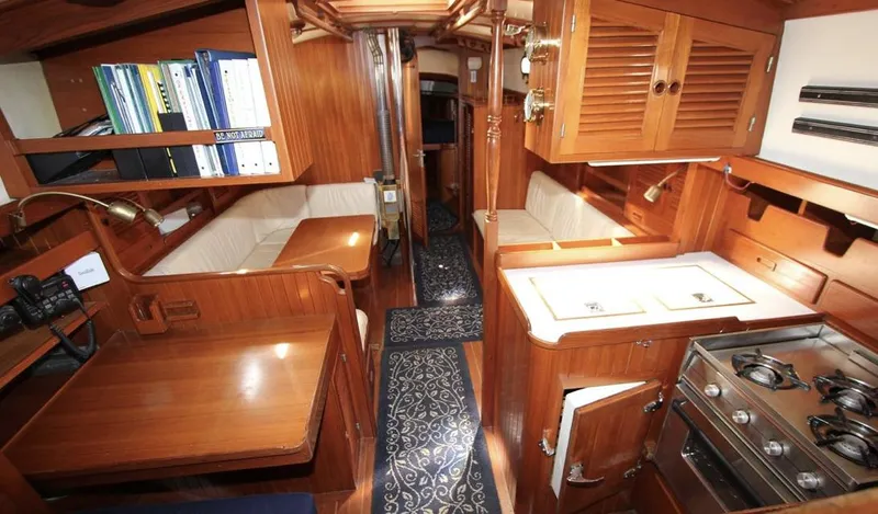 Slide: The Image of 1984 Tayana Sloop Rigged Cutter interior with wood finish, kitchen, and seating area. - 9